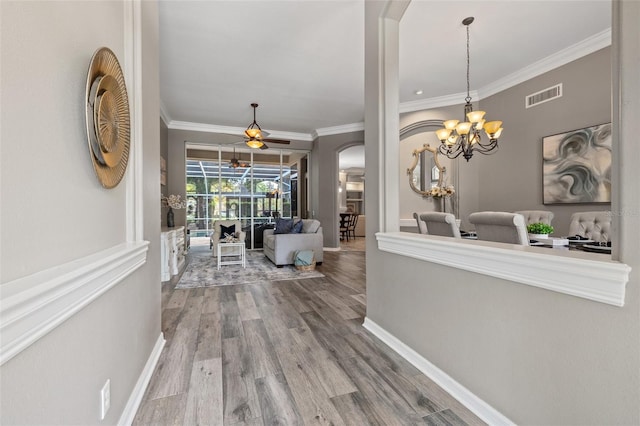 corridor featuring wood-type flooring, crown molding, and a notable chandelier