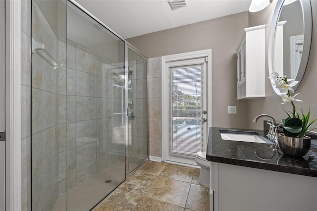 bathroom featuring toilet, vanity, and walk in shower