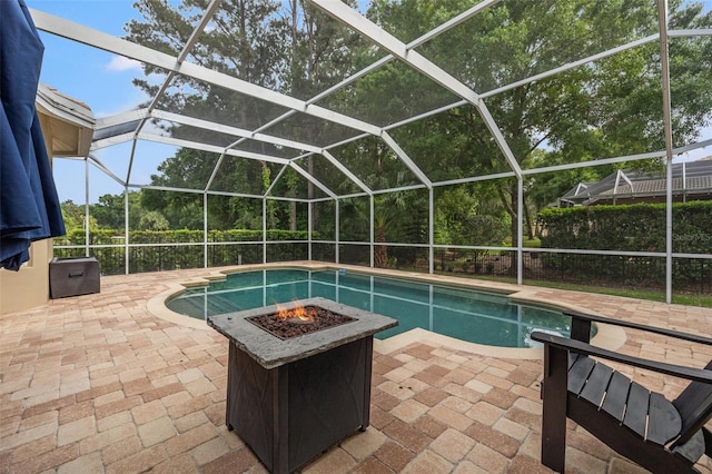 view of swimming pool featuring a lanai, a patio, and an outdoor fire pit