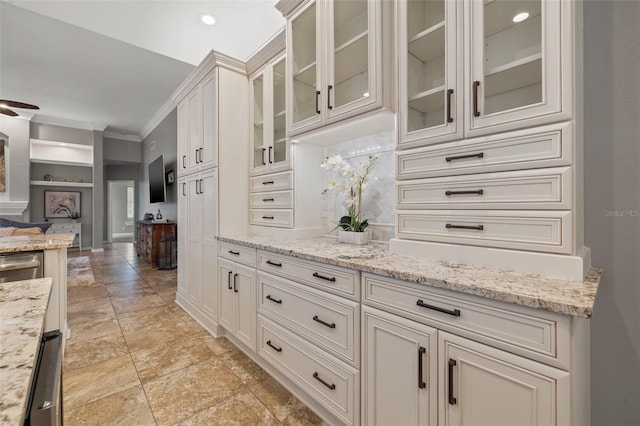 kitchen featuring light stone countertops, white cabinets, and ornamental molding