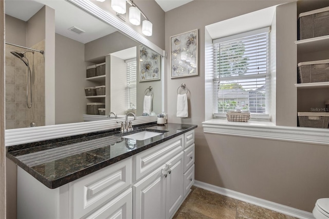 bathroom featuring a tile shower, vanity, and toilet