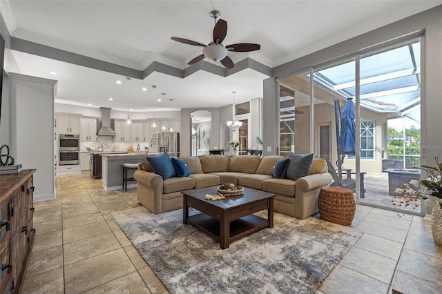 tiled living room featuring ceiling fan with notable chandelier and crown molding