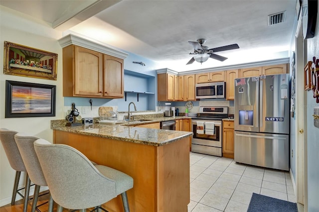 kitchen featuring appliances with stainless steel finishes, ceiling fan, kitchen peninsula, and a breakfast bar area