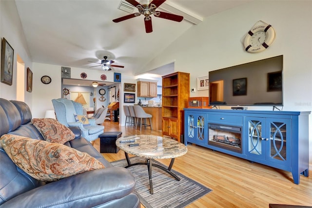 living room with ceiling fan, vaulted ceiling with beams, and light hardwood / wood-style flooring