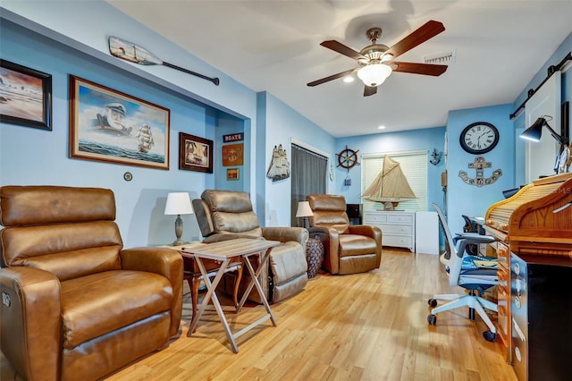 living room featuring ceiling fan, a barn door, and light hardwood / wood-style flooring