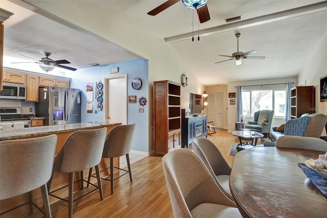 dining room with ceiling fan, light hardwood / wood-style floors, and vaulted ceiling