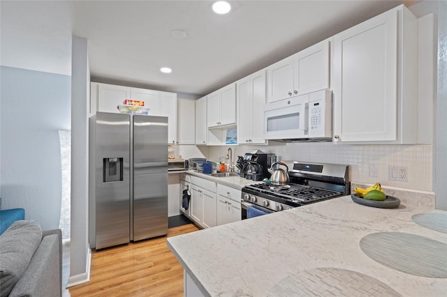 kitchen featuring white cabinets, sink, light hardwood / wood-style flooring, appliances with stainless steel finishes, and tasteful backsplash