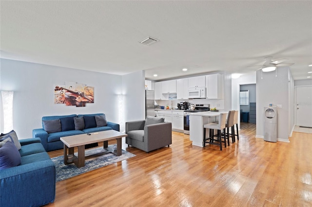 living room featuring light hardwood / wood-style flooring and ceiling fan