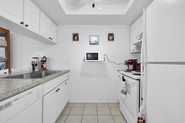 kitchen featuring backsplash, white appliances, a tray ceiling, and white cabinetry