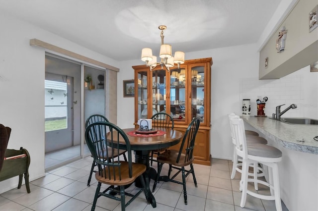 dining space with light tile flooring, sink, and an inviting chandelier