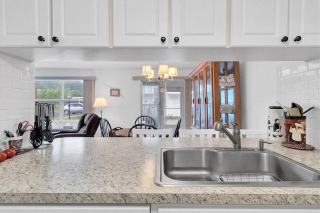 kitchen with white cabinets, sink, tasteful backsplash, and a chandelier