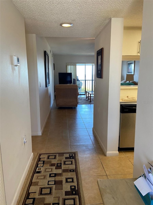 corridor with a textured ceiling and light tile floors