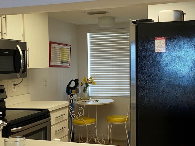 kitchen with backsplash, white cabinetry, stainless steel appliances, and a breakfast bar