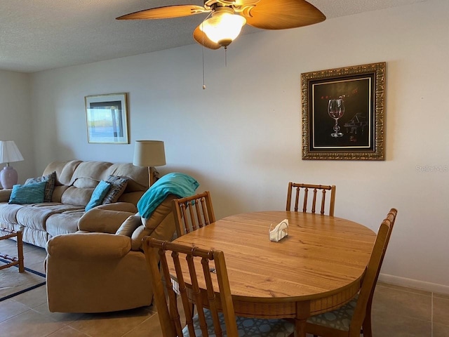 tiled dining space with a textured ceiling and ceiling fan