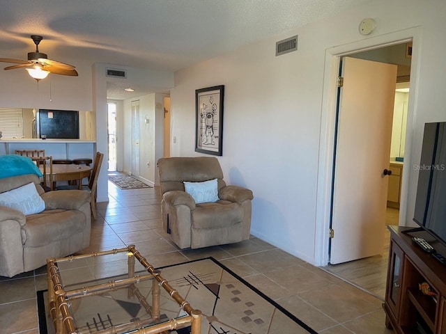 living room featuring a textured ceiling, ceiling fan, and tile flooring