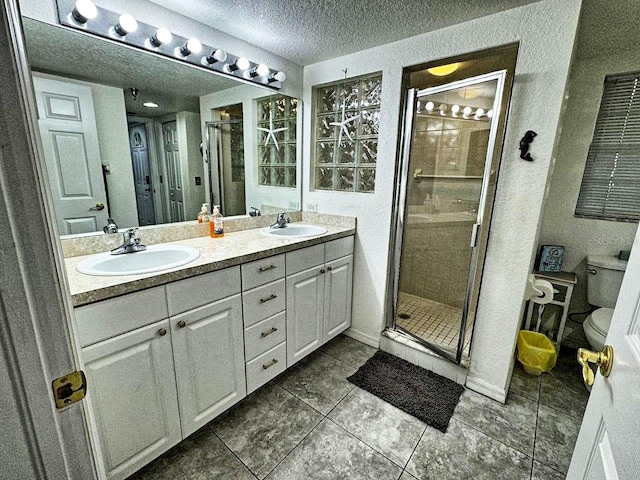 bathroom featuring large vanity, toilet, tile flooring, an enclosed shower, and dual sinks