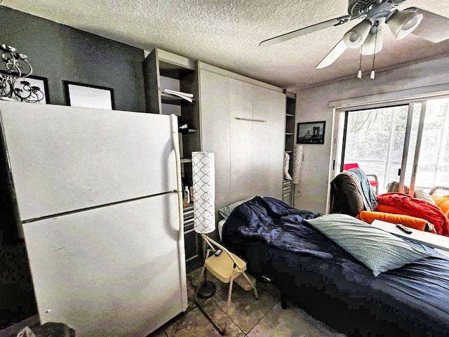 bedroom with tile floors, white fridge, ceiling fan, and a textured ceiling