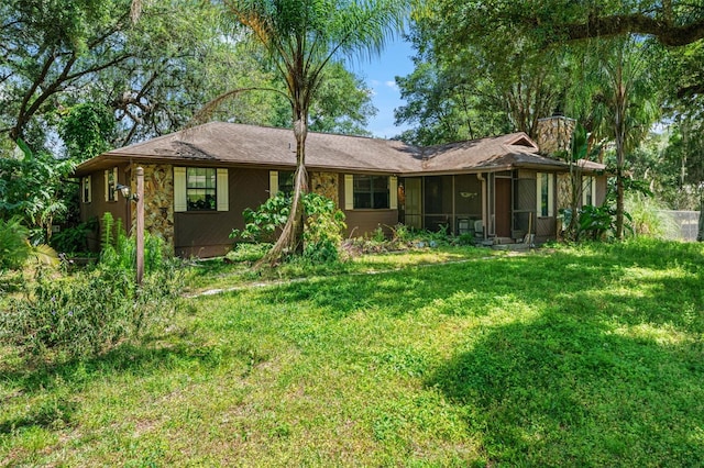 rear view of house featuring a sunroom and a lawn