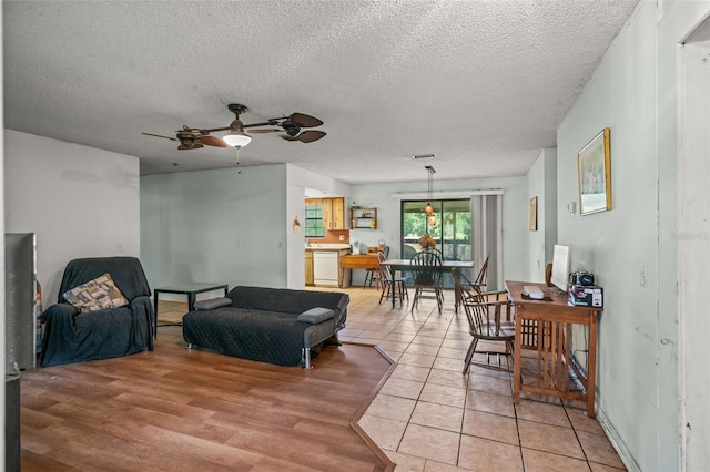 living room with ceiling fan, hardwood / wood-style flooring, and a textured ceiling