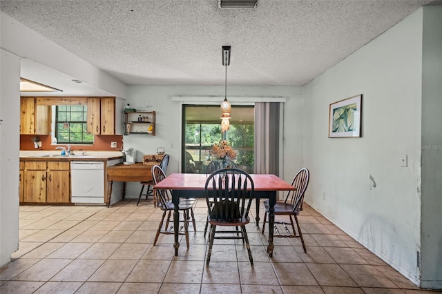 dining space featuring sink, a textured ceiling, and light tile flooring