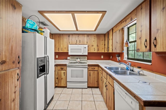 kitchen with tile countertops, white appliances, sink, and light tile floors