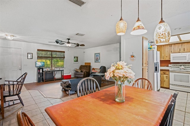 tiled dining area featuring a textured ceiling and ceiling fan