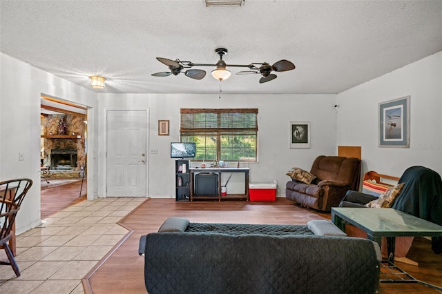 living room featuring a textured ceiling, ceiling fan, and tile flooring