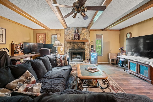 living room featuring a fireplace, beam ceiling, hardwood / wood-style flooring, ceiling fan, and a textured ceiling