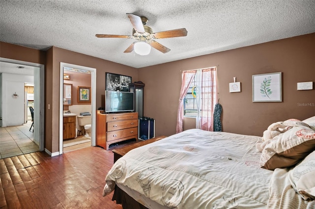 bedroom with wood-type flooring, ceiling fan, ensuite bathroom, and a textured ceiling