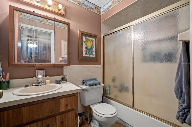 full bathroom featuring vanity, toilet, tile walls, and bath / shower combo with glass door