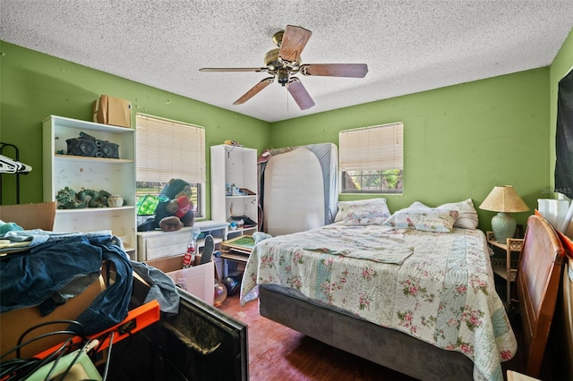 bedroom with wood-type flooring, a textured ceiling, and ceiling fan