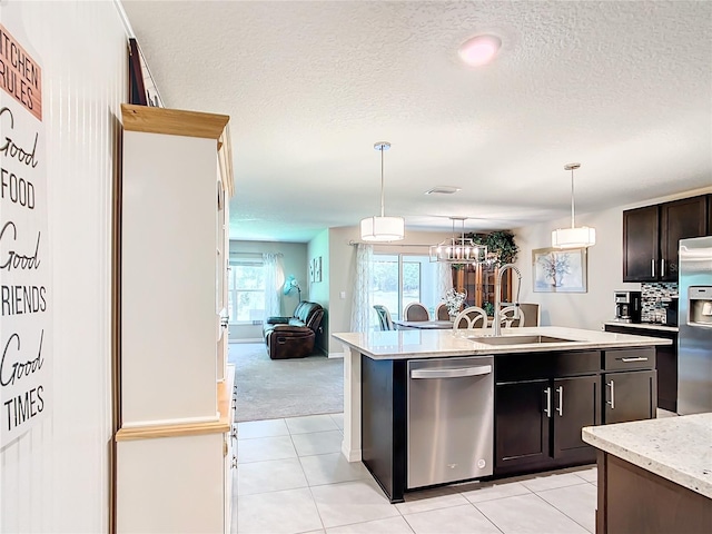 kitchen with appliances with stainless steel finishes, hanging light fixtures, a center island with sink, light tile flooring, and sink