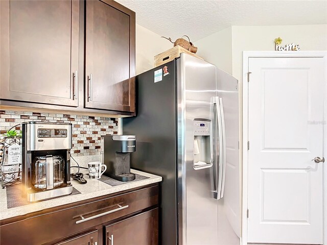 kitchen with stainless steel fridge with ice dispenser, tasteful backsplash, dark brown cabinetry, and a textured ceiling