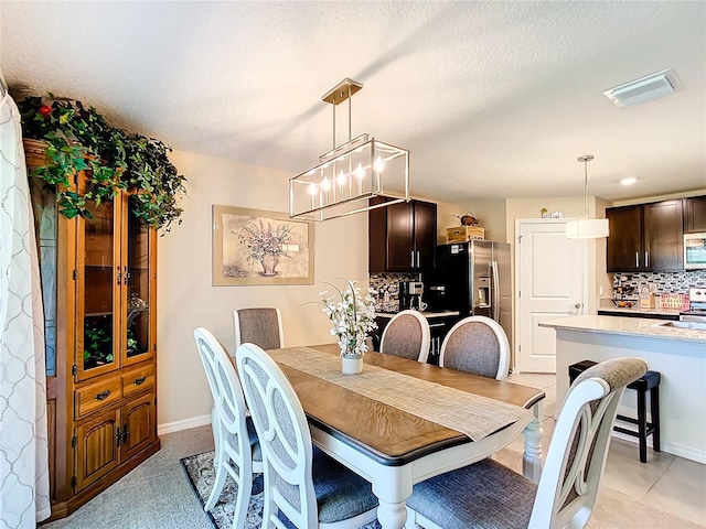 dining space with a textured ceiling, a notable chandelier, and light tile flooring