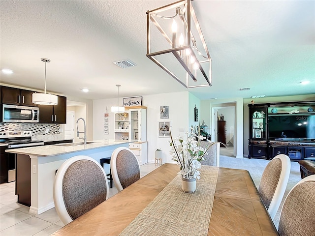 dining space with a textured ceiling, sink, and light tile flooring