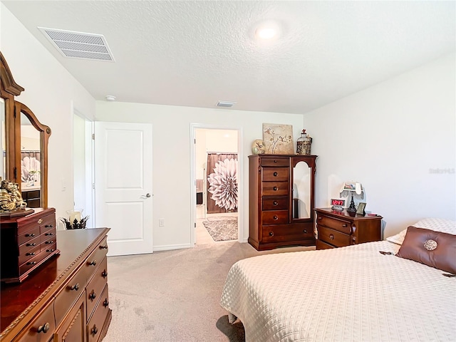 bedroom featuring light carpet, a textured ceiling, and ensuite bathroom