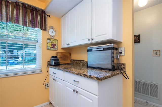 kitchen featuring white cabinets, plenty of natural light, and light tile floors