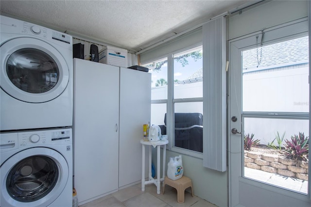 washroom featuring stacked washer / drying machine, light tile floors, a wealth of natural light, and a textured ceiling