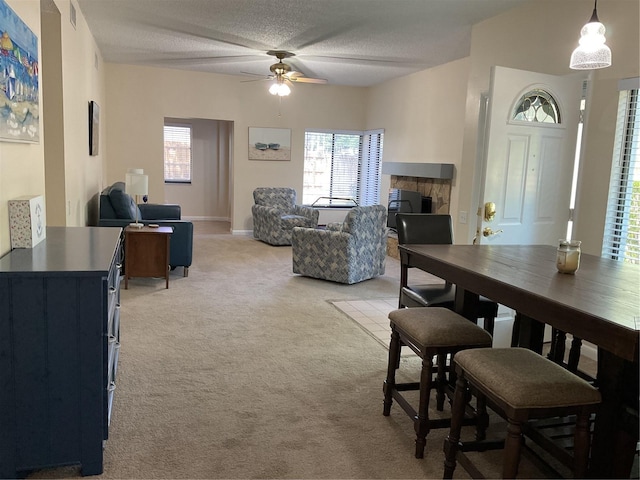 carpeted dining area with a textured ceiling and ceiling fan