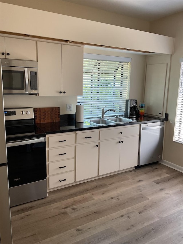 kitchen with sink, light wood-type flooring, stainless steel appliances, and white cabinets