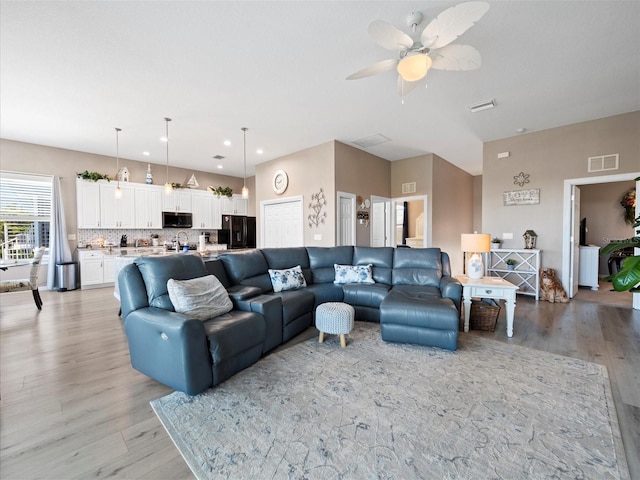 living room with light hardwood / wood-style flooring and ceiling fan