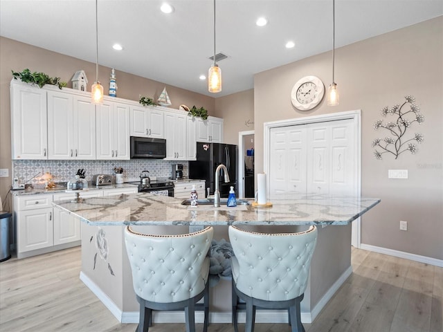 kitchen featuring a large island, light hardwood / wood-style flooring, decorative light fixtures, and electric stove