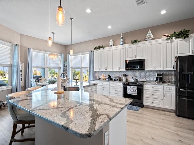 kitchen with range with electric cooktop, white cabinets, backsplash, a spacious island, and black fridge