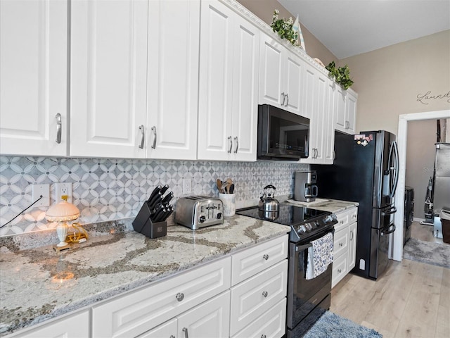 kitchen with white cabinets, light stone countertops, black appliances, backsplash, and light hardwood / wood-style floors