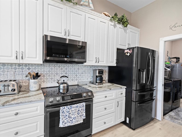 kitchen featuring appliances with stainless steel finishes, light hardwood / wood-style flooring, backsplash, washing machine and clothes dryer, and white cabinetry