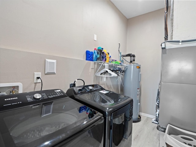 clothes washing area featuring hookup for a washing machine, light hardwood / wood-style floors, independent washer and dryer, electric dryer hookup, and electric water heater