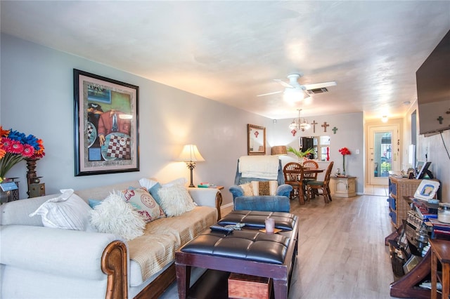 living room with hardwood / wood-style floors and ceiling fan with notable chandelier