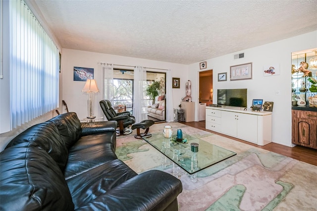 living room with a textured ceiling and light wood-type flooring