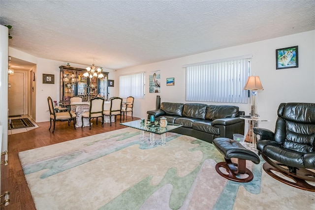 living room featuring an inviting chandelier, dark hardwood / wood-style flooring, and a textured ceiling