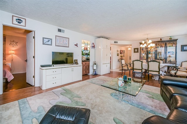 living room featuring a chandelier, hardwood / wood-style flooring, and a textured ceiling